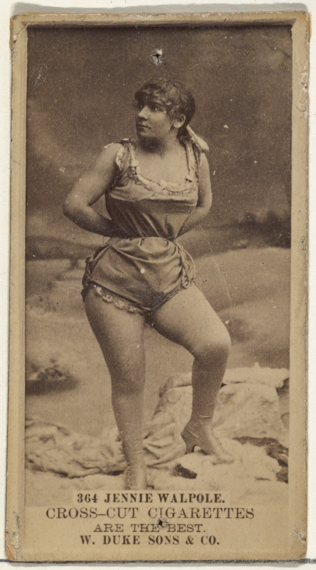 Ein Schwarz-Weiß-Foto einer älteren Frau in einem vintage-Badeanzug, die selbstbewusst am Strand steht, mit einem Dutt, geschlossenen Augen und leicht geöffneten Lippen in einer friedlichen expression.