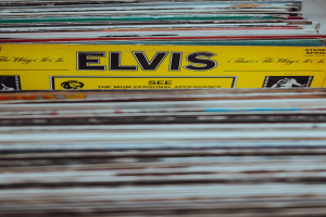 Stapel von Elvis-Presley-Platten ordentlich auf einem Tisch mit sichtbaren Titeln und einem leicht unscharfen, träumerischen Hintergrund.