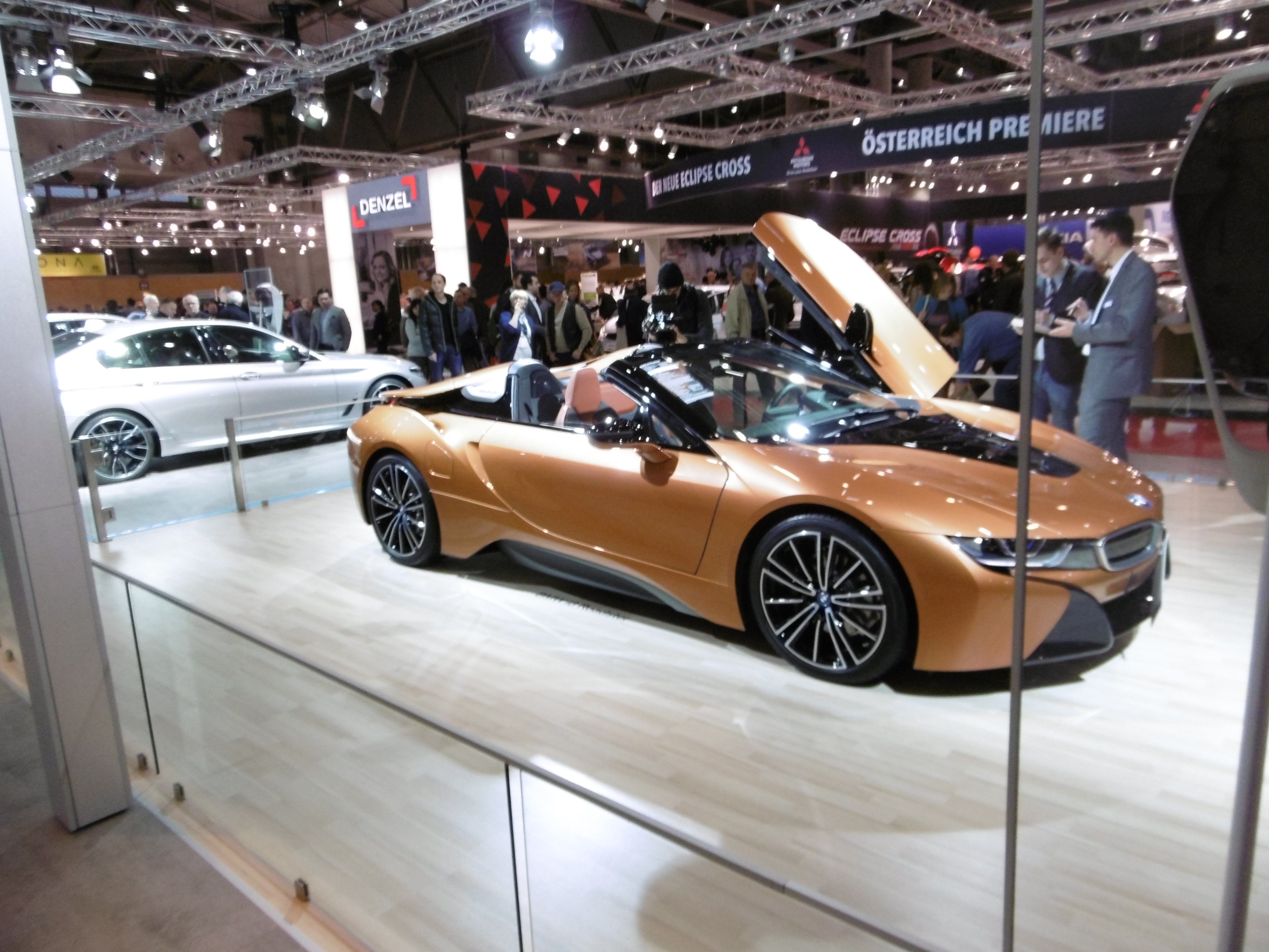 Ein schickes schwarzes BMW i8 Roadster mit Chromakzenten auf der Frankfurt Motor Show umgeben von formell gekleideten Gästen.