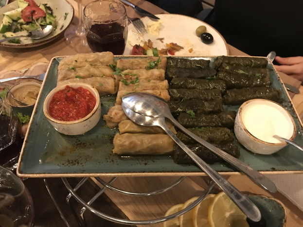 Ein Esstisch mit Tellern voller Essen, Weingläsern und Besteck, in einem Restaurant oder einer Bar in Athen, Griechenland, zu sehen.