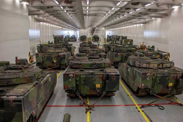 Ein grosser Militaraerraum mit Reihen von Militaraerfahrzeugen, Wanden an beiden Seiten und Deckeneinbauleuchten.