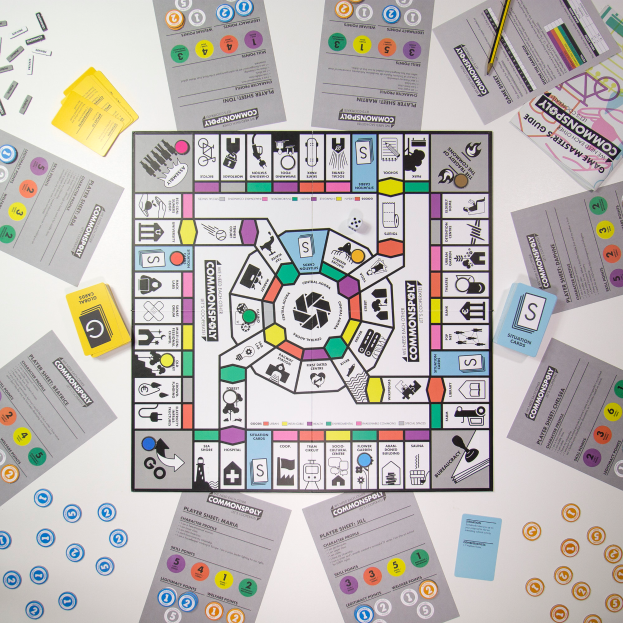 Ein Monopoly-Spielbrett ist auf einem Tisch umgeben von verschiedenen Karten, Papieren und einem Bleistift aufgebaut.