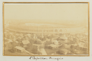Altes Schwarz-Weiß-Foto eines Stadions umgeben von Stadtgebäuden, Bäumen und Strommasten, mit Text unten.