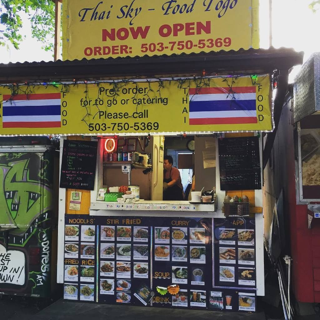 Läden, Getränkedosen, Speisekarten, eine Uhr, Gewürze in Plastikbehältern, Würzmittel, Werbetafeln, Namensschilder und Himmel.