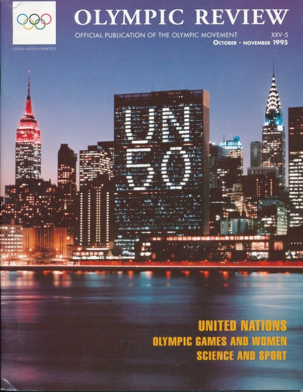 Buch mit dem Titel "Olympic Review Offizielle Veröffentlichung der Olympischen Bewegung" mit einer Stadtansicht auf dem Cover, das auf einer flachen Oberfläche liegt.