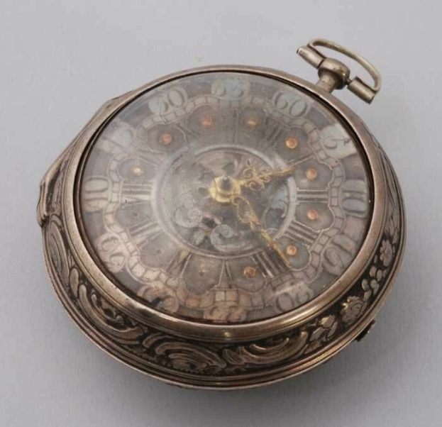 Eine silberne Taschenuhr mit floralem Design auf dem Zifferblatt, aus dem 18. Jahrhundert, vor einem weißen Hintergrund.