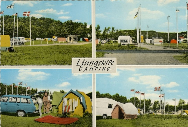 Eine Postkarte zeigt einen Campingplatz mit einem geparkten Auto, Zelten, Menschen, Fahnen, Pfählen, Bäumen, einer Straße, einem bewölkten Himmel und einer Texttafel im Vordergrund.