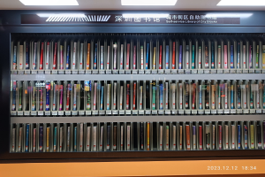 Eine gut beleuchtete Bibliothek mit hohen Bücherregalen voller Bücher, die ein Schild mit Text und ein Wasserzeichen am Boden zeigt, ähnlich einer Selbstbedienungsbibliothek der Stadtviertel.