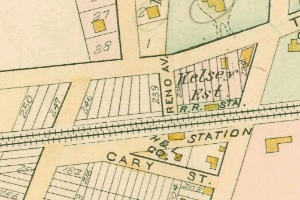 Alte Karte einer dicht bebauten Stadt mit nummerierten Grundstücken, Textanmerkungen und einer 'Grundstück-zu-Verkauf'-Anzeige unten.