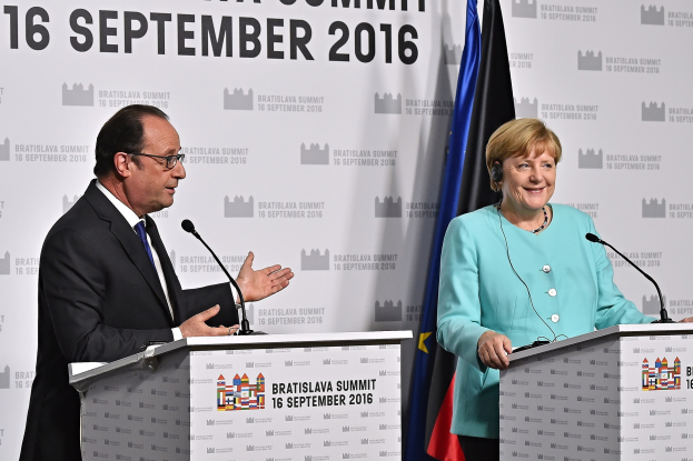 Bundeskanzlerin Angela Merkel und Frankreichs Präsident François Hollande stehen an Rednerpulten mit Mikrophonen, lachend, mit einem "Bratislava-Gipfel 2016"-Plakat im Hintergrund.