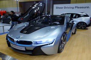 Ein BMW i8-Konzeptfahrzeug auf der Frankfurter Motor Show, umgeben von Menschen in Abendgarderobe, das seine schlanke, glänzende schwarze Design mit einer großen, gebögen Motorhaube, niedriger Karosserie, breiter Stand und sportlichen Scheinwerfern präsentiert.
