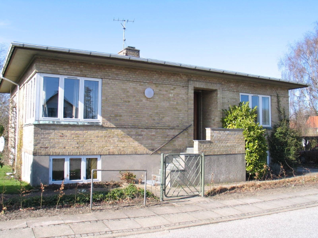 Ein zweistöckiges Einfamilienhaus zum Verkauf in St Johns Wood, Swindon, mit einem Dach, Fenstern, einer Tür, einer Treppe, einem Metallzaun, Pflanzen, Gras, Bäumen, einer Satellitenschüssel und einer bewölkten Himmel.