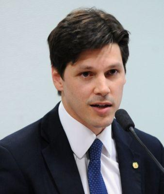 Ein Mann im Anzug spricht in ein Mikrofon, wahrscheinlich um die Genehmigung eines Gesetzes durch die Regierung zu kommentieren.