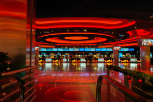 Ein Casino-Innenraum Mit Einem Weihnachtsbaum In Der Mitte, Fliesenboden, Geländer Auf Beiden Seiten, Dekorative Säulen, Deckenbeleuchtung Und Eine Festliche Menge Im Hintergrund.